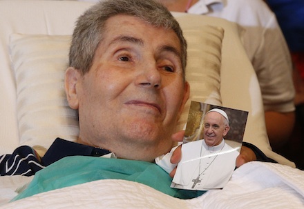 Sick person holds photo of Pope Francis after being blessed by pontiff in Cagliari